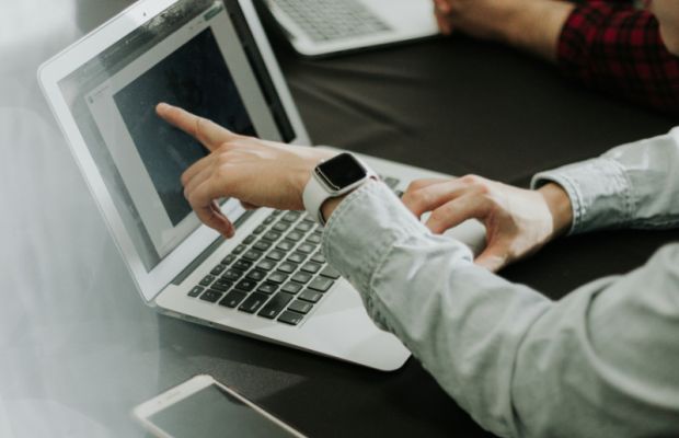 Designer pointing at logo design on laptop screen during creative process