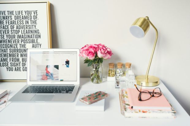 Laptop on desk with notepad and glasses, representing blog article writing