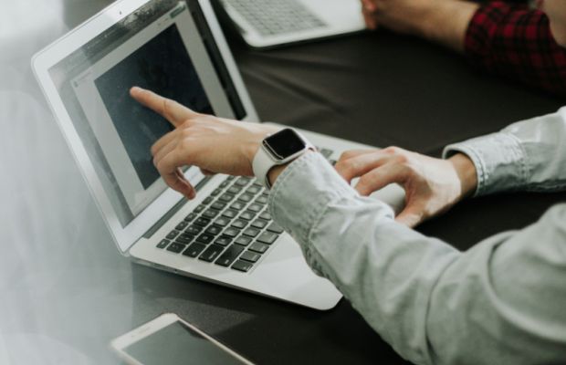 Designer pointing at logo design on laptop screen during creative process